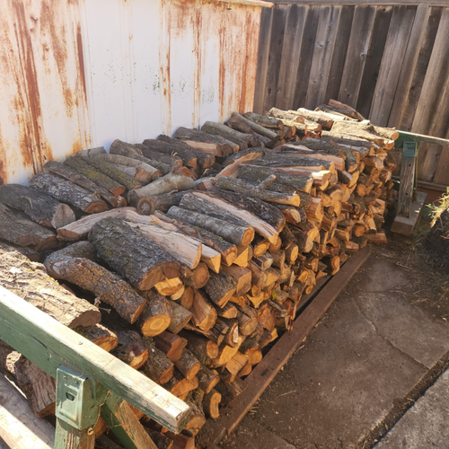  1 cord Stack of almond firewood on wooden pallets against a wooden fence delivered in Petaluma CA.