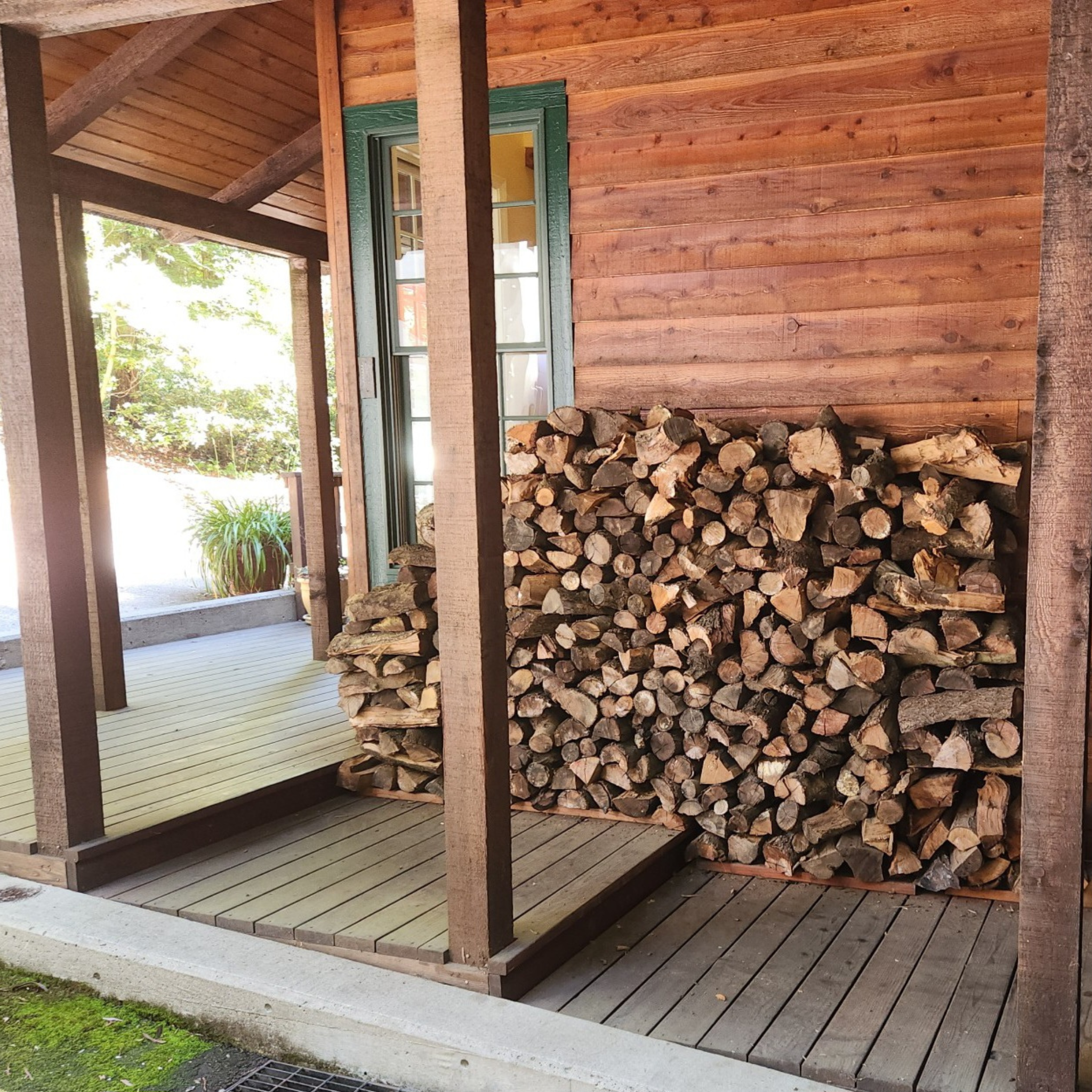 Stack of firewood on a wooden deck next to a cabin
