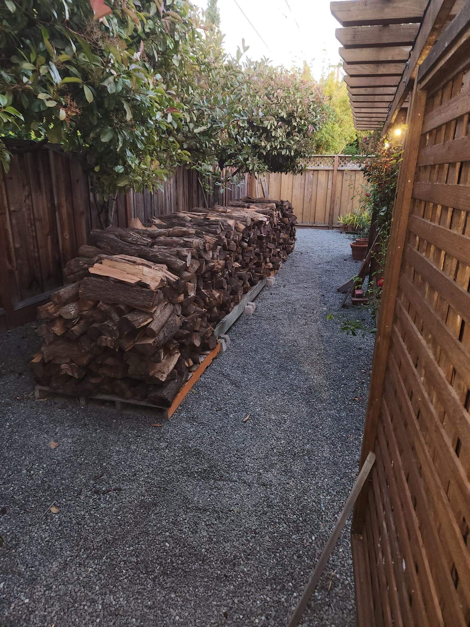 2 cord stack of almond firewood against a wooden fence delivered to San Jose CA.