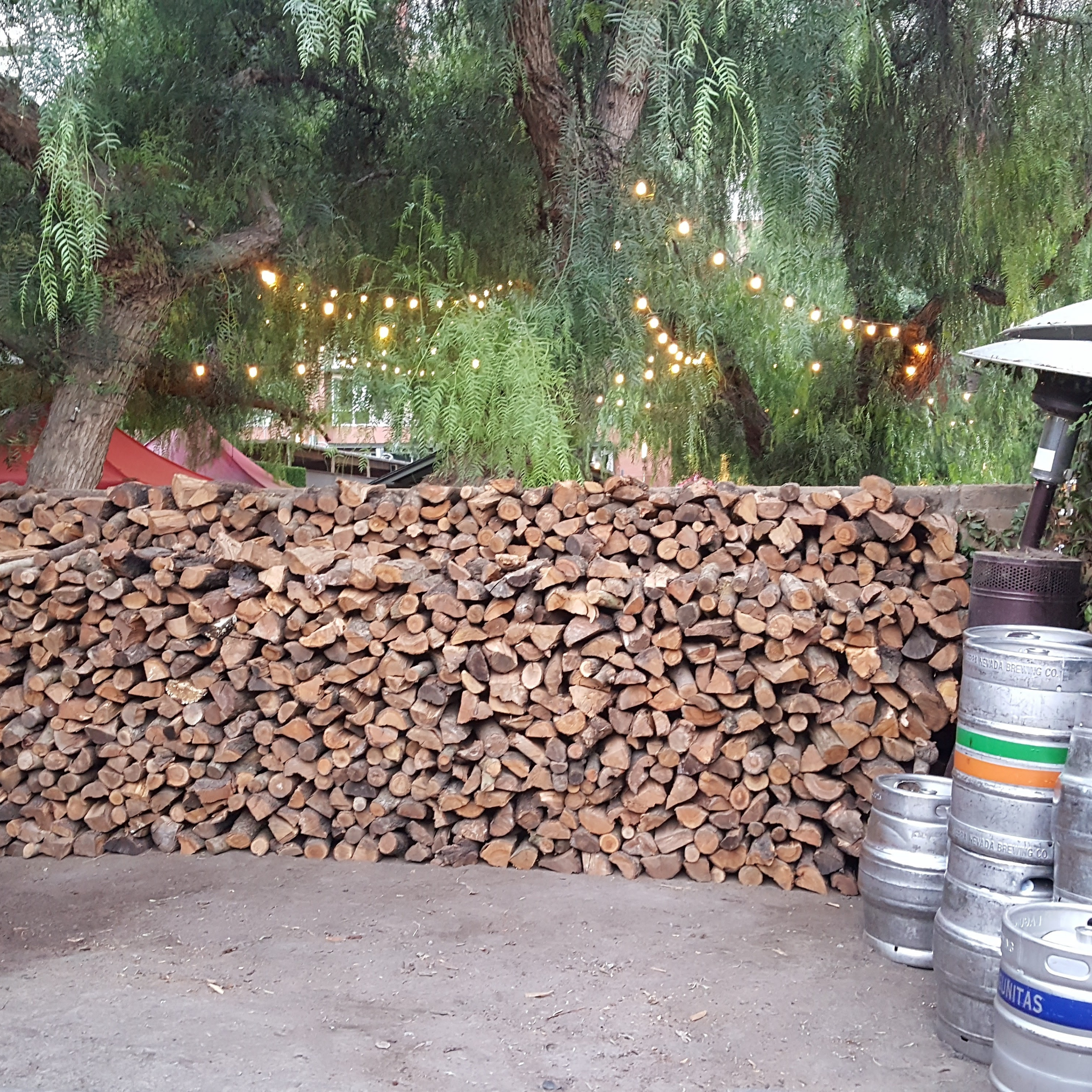 2 cords stacked pile of cut almond firewood logs aglong the back wall of the outdoor patio setting in restaurant in San Jose Ca. 