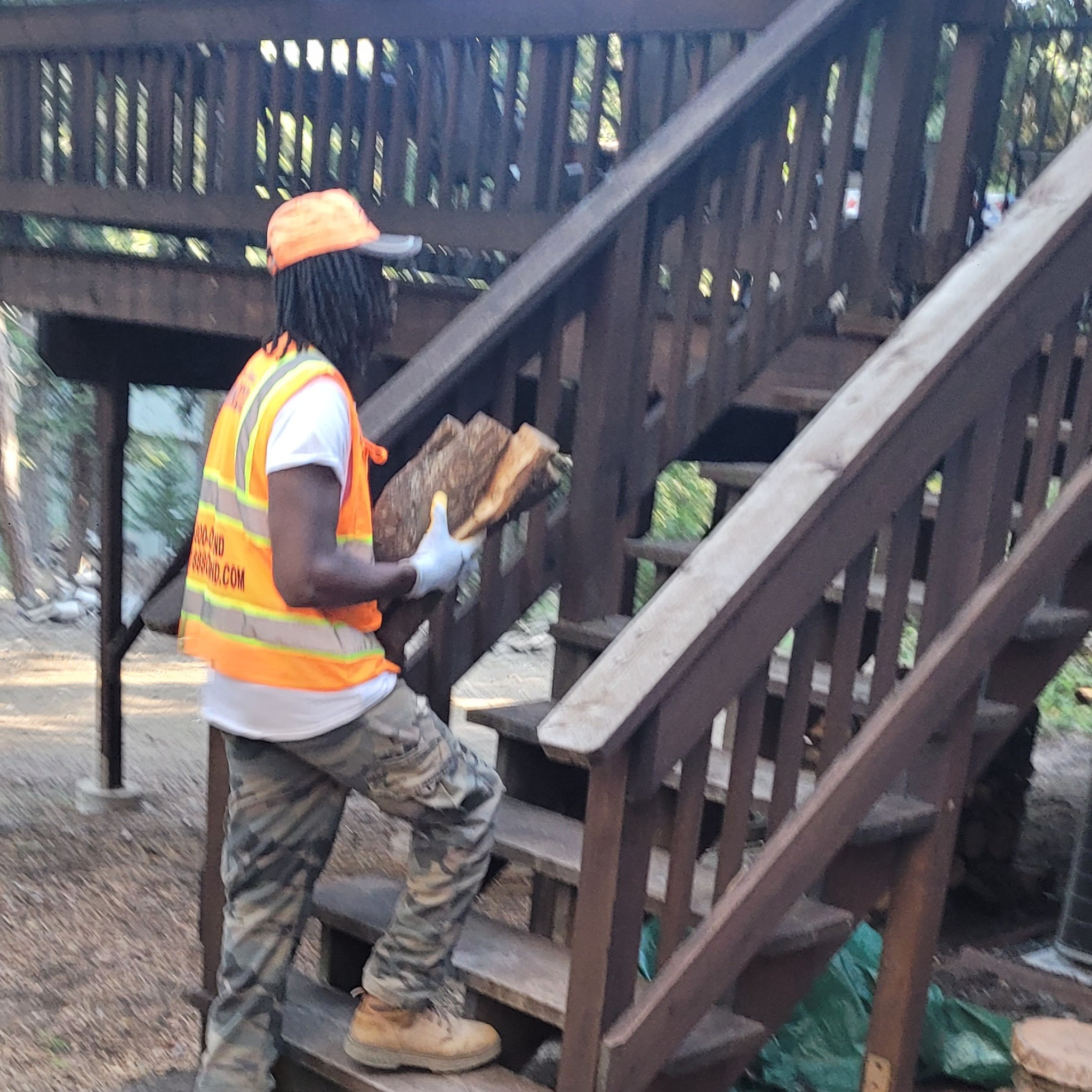 Steve Sims delivery worker carrying almond firewood upstairs for stacking at customers home. 